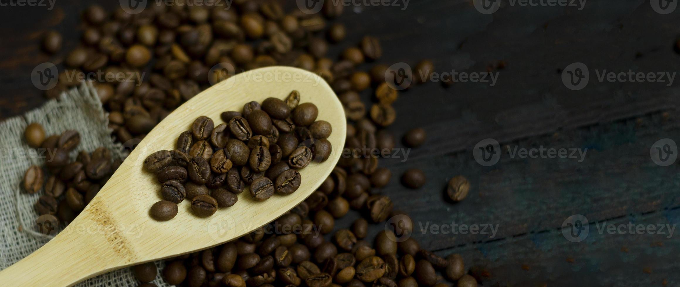 cuchara de madera con granos de café sobre fondo de café rústico foto