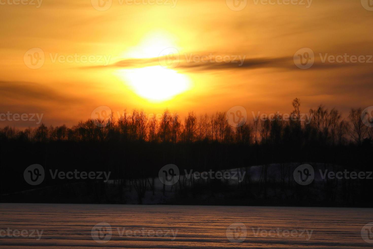 Sunset over forest on frozen lake landscape photo