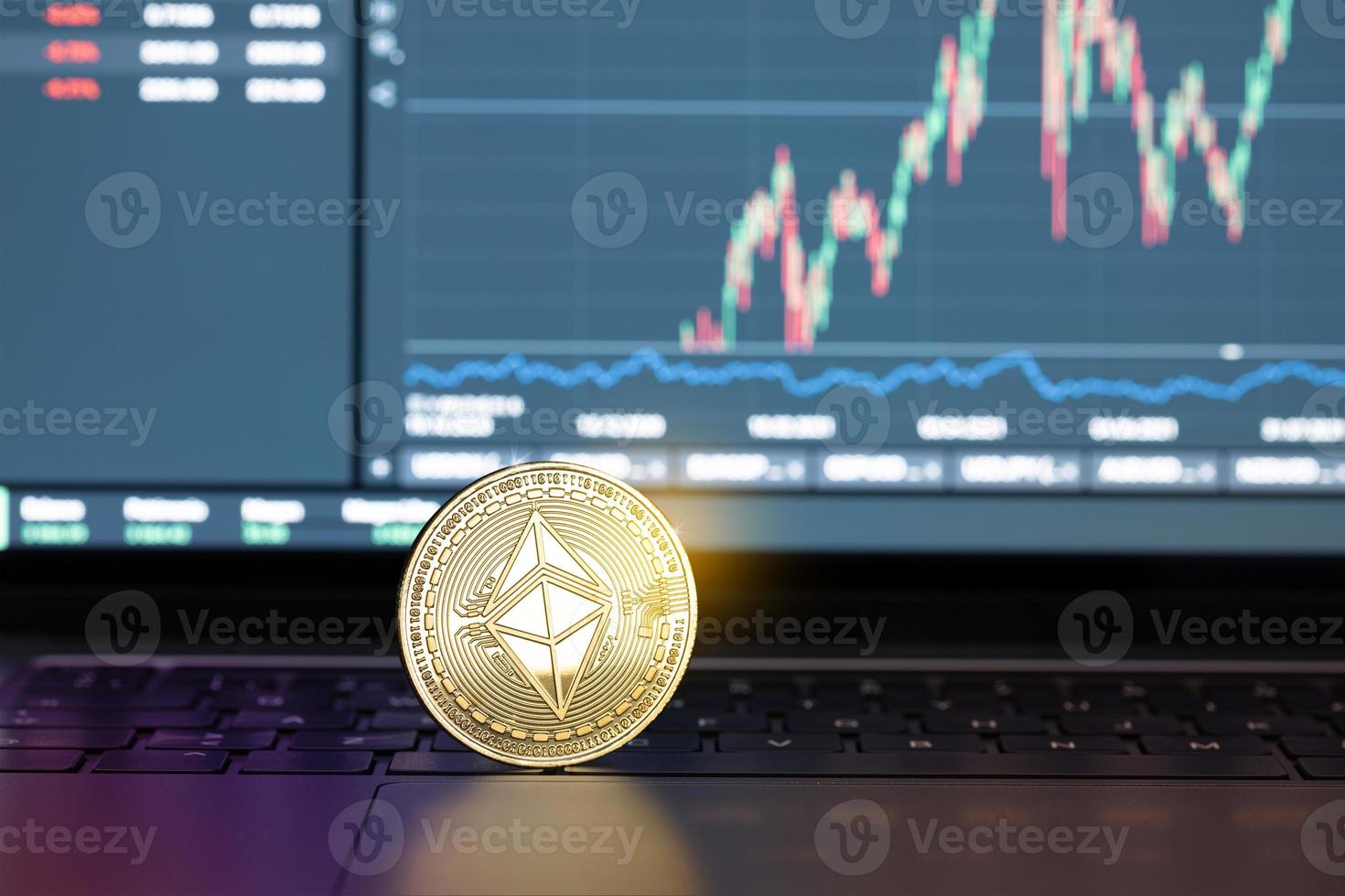 Ethereum coin on laptop and chart on display at background. Cryptocurrency trading or investment concept photo