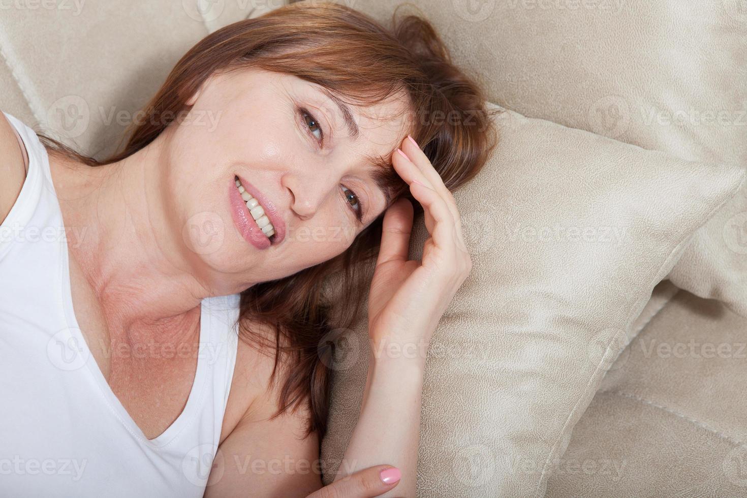 Good morning concept. Portrait of middle age woman lying on bed background. Top view and mock up. Menopause photo