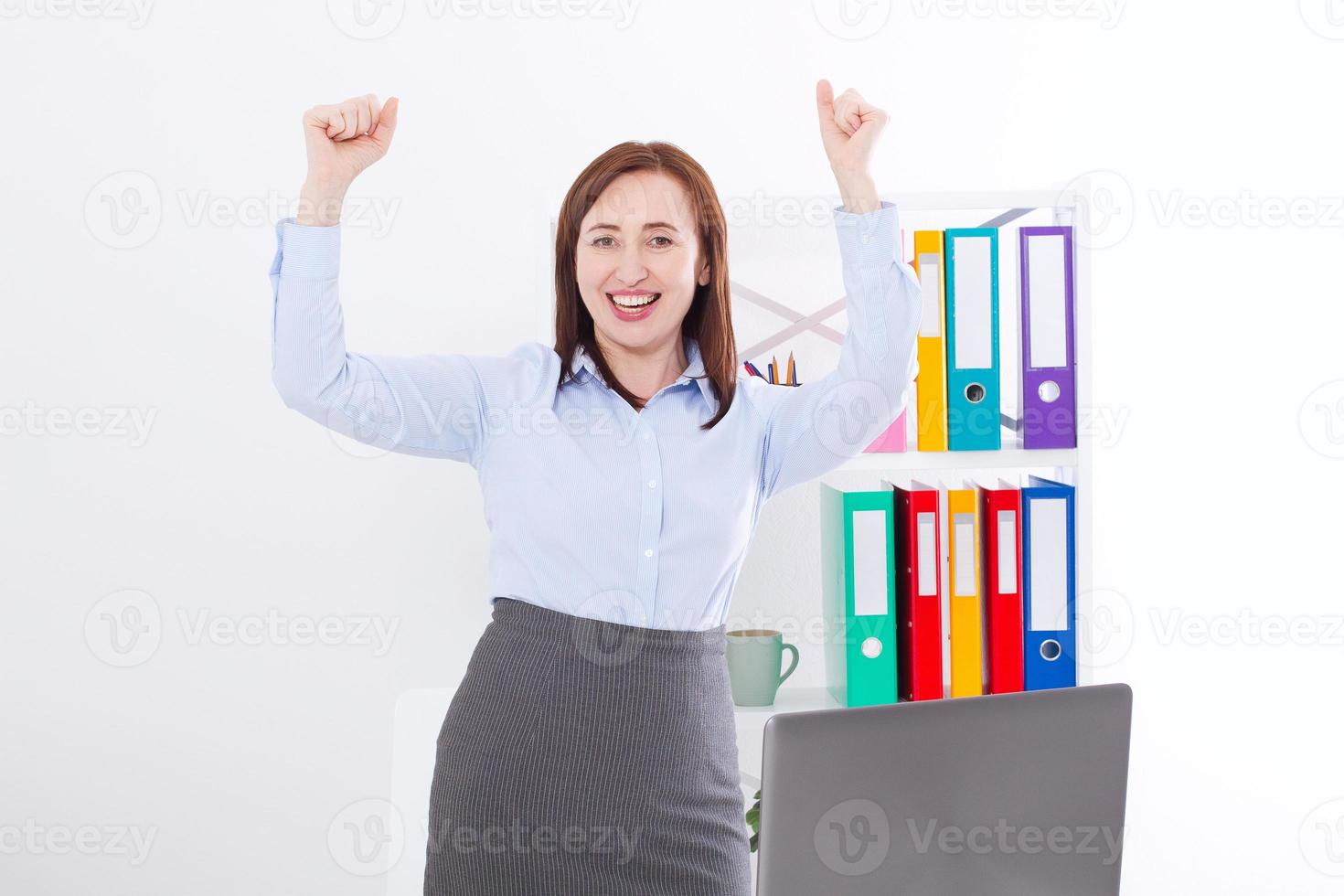 mujer de negocios feliz y exitosa levantando los brazos en el fondo de la oficina y celebrando el éxito aislado en blanco. simular y copiar espacio. concepto de negocio foto