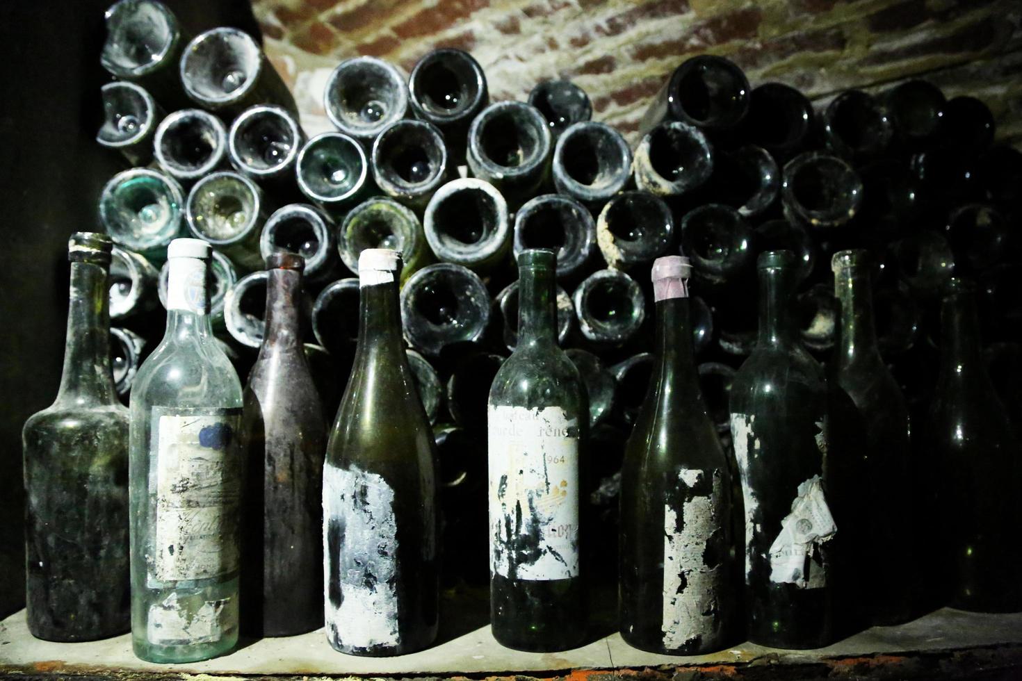 Very ancient bottles of wine lies in retro dark cellar photo