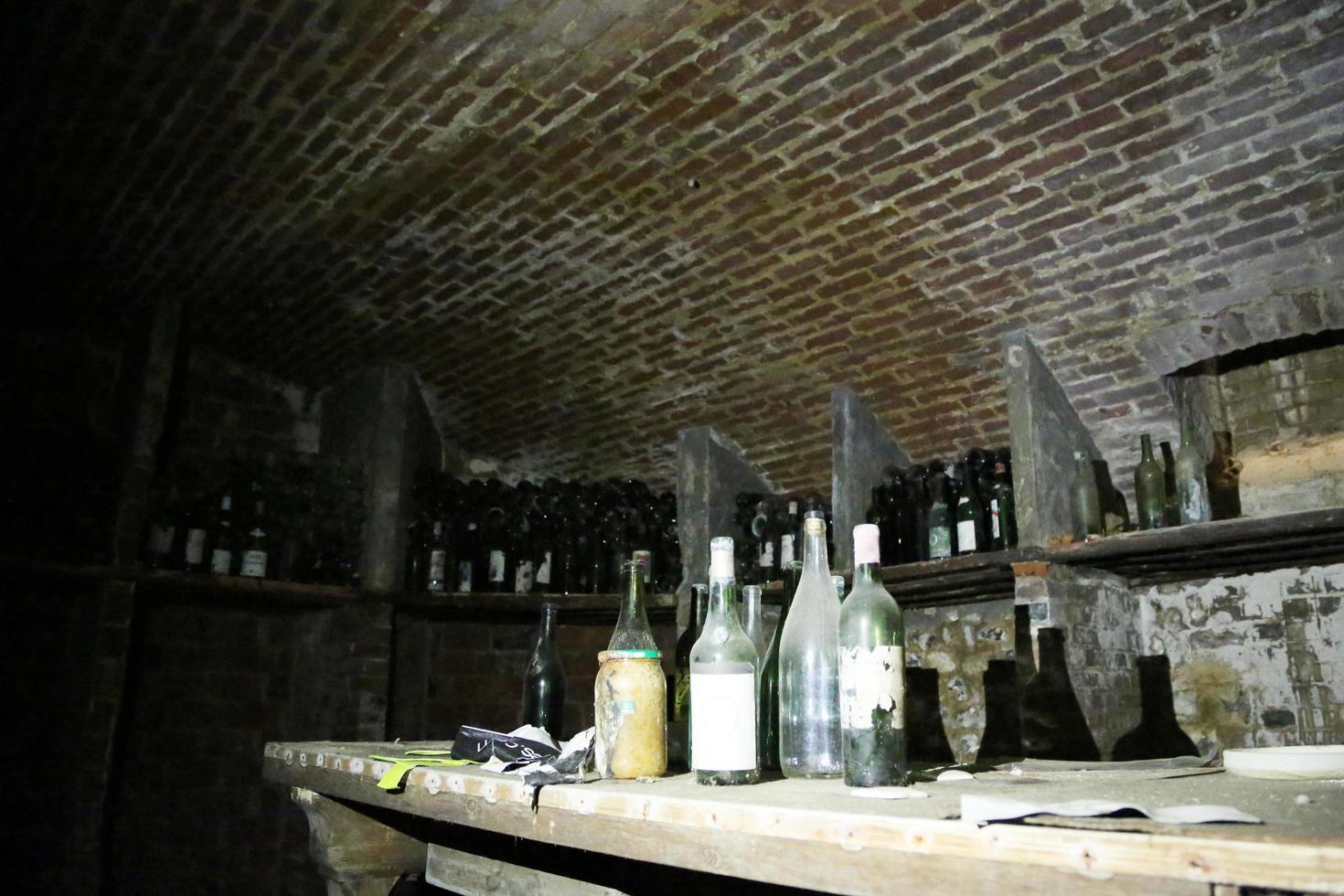 Very ancient bottles of wine lies in retro dark cellar photo