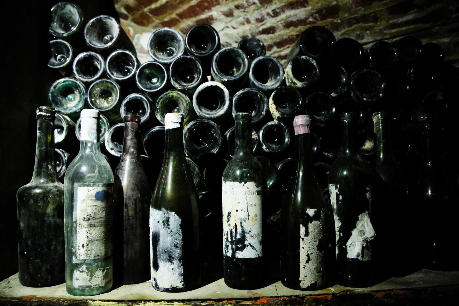 Very ancient bottles of wine lies in retro dark cellar photo