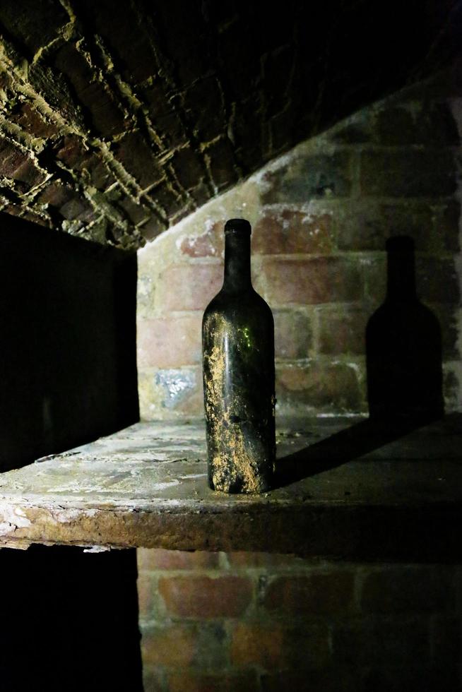 Very ancient bottles of wine lies in retro dark cellar photo