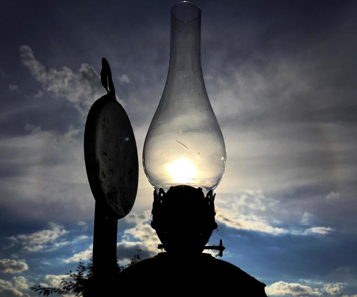 Old kerosene lamp burning with bright sun flame photo