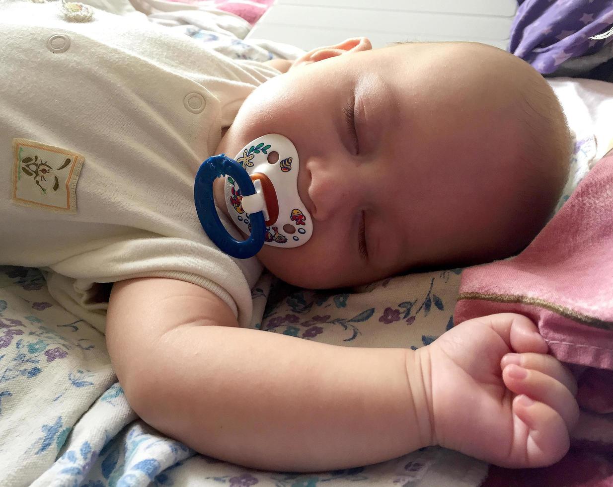 Sleeping baby boy with child pacifier posing photographer for color photo