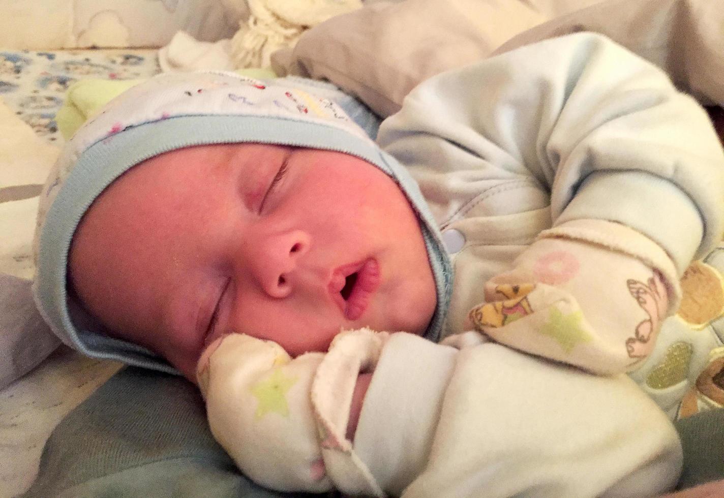 Beautiful sleeping baby boy with child hat posing photographer for color photo