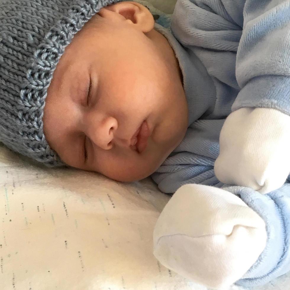 Beautiful sleeping baby boy with child hat posing photographer for color photo