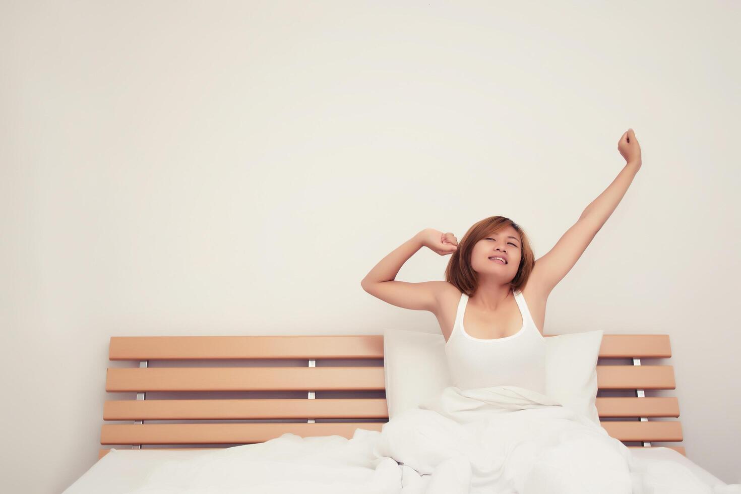 Beautiful young woman stretching on bed after wake up in the morning photo