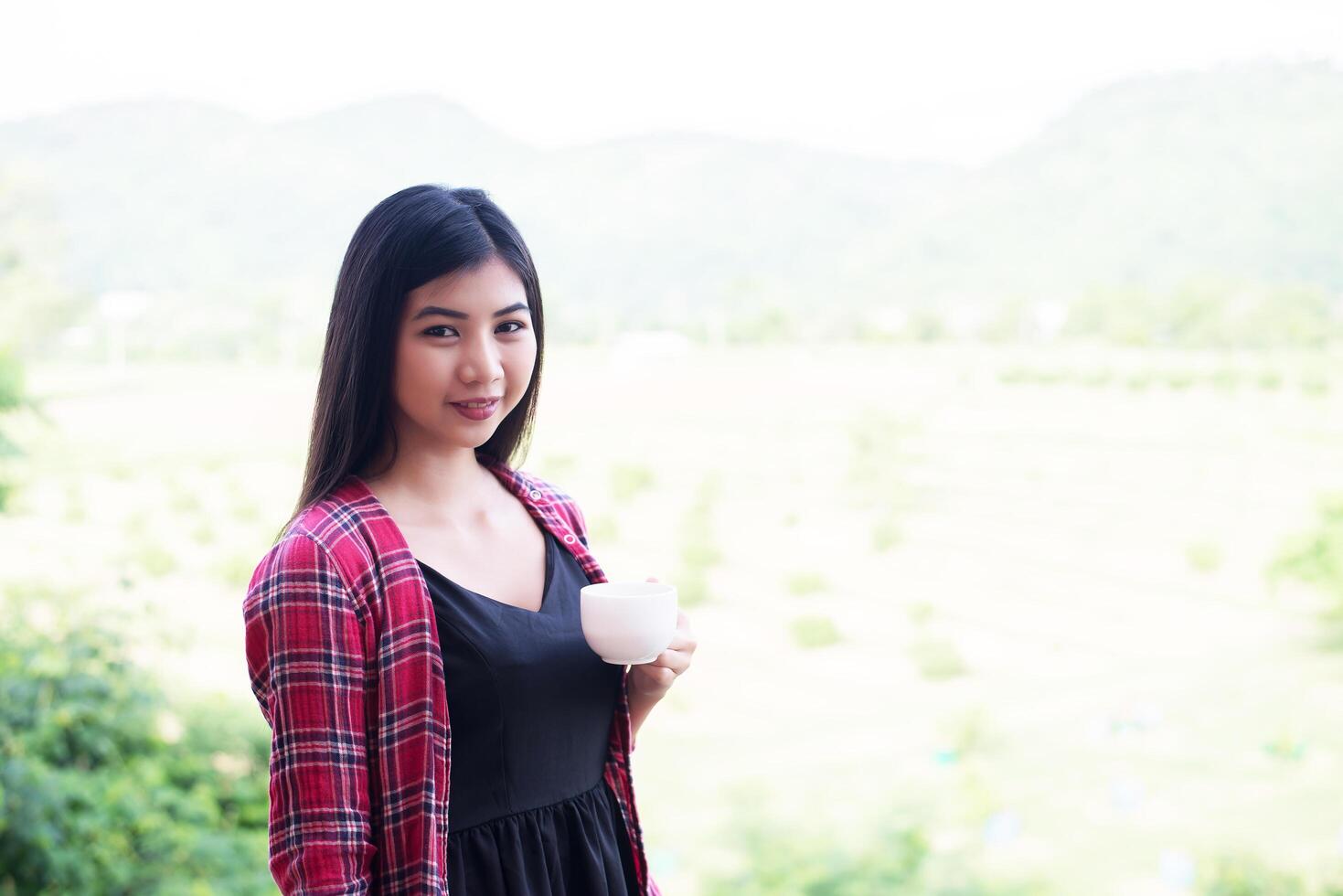 Portrait of the beautiful woman holding a cup of coffee in the morning,mountain view behind. photo