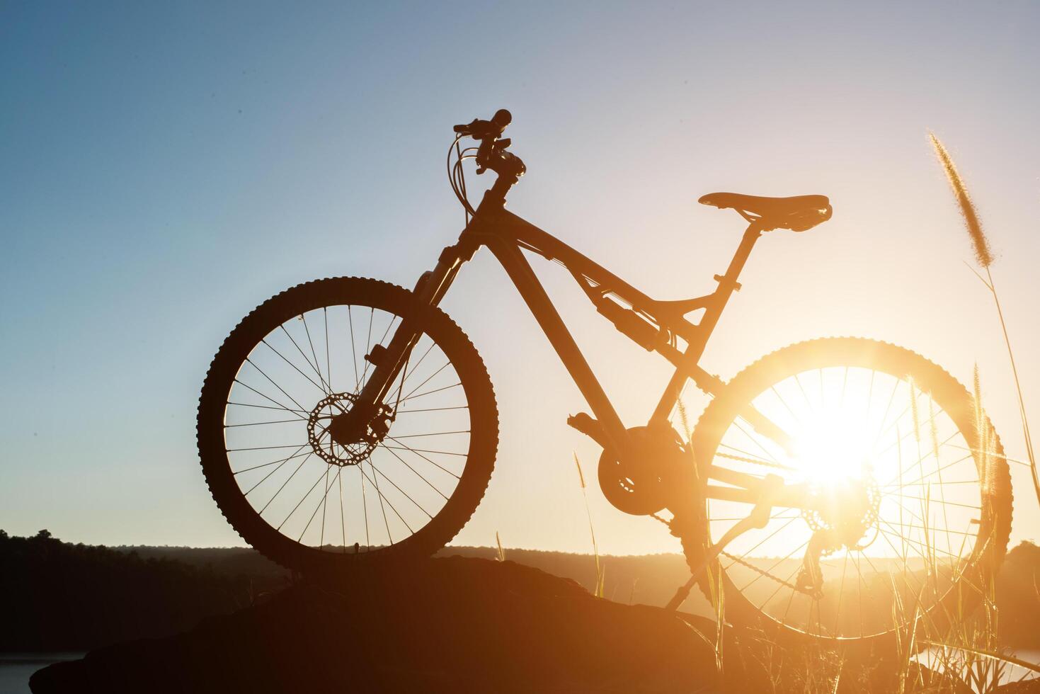 Silhouette Mountain biking on the rock at sky sunset photo