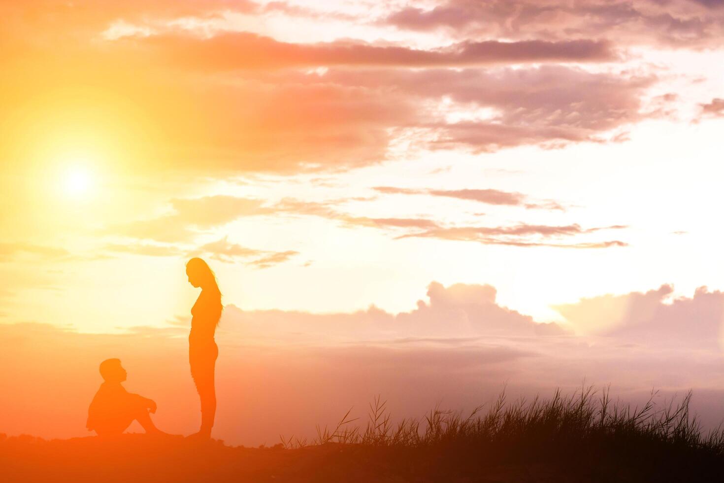 Mother encouraged her son outdoors at sunset, silhouette concept photo