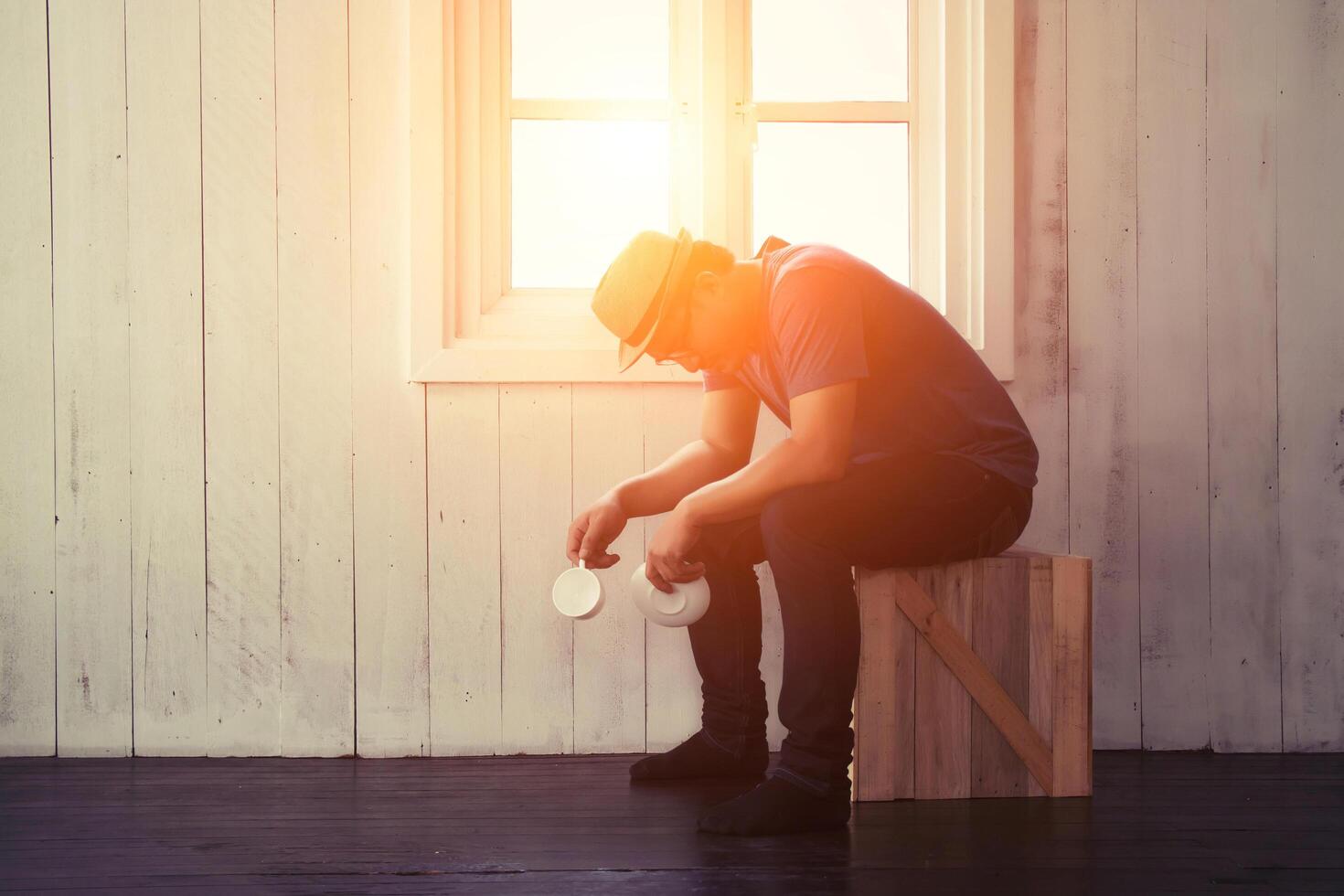 handsome man holding a cup out off coffee down on the floor and his face  look so serious photo