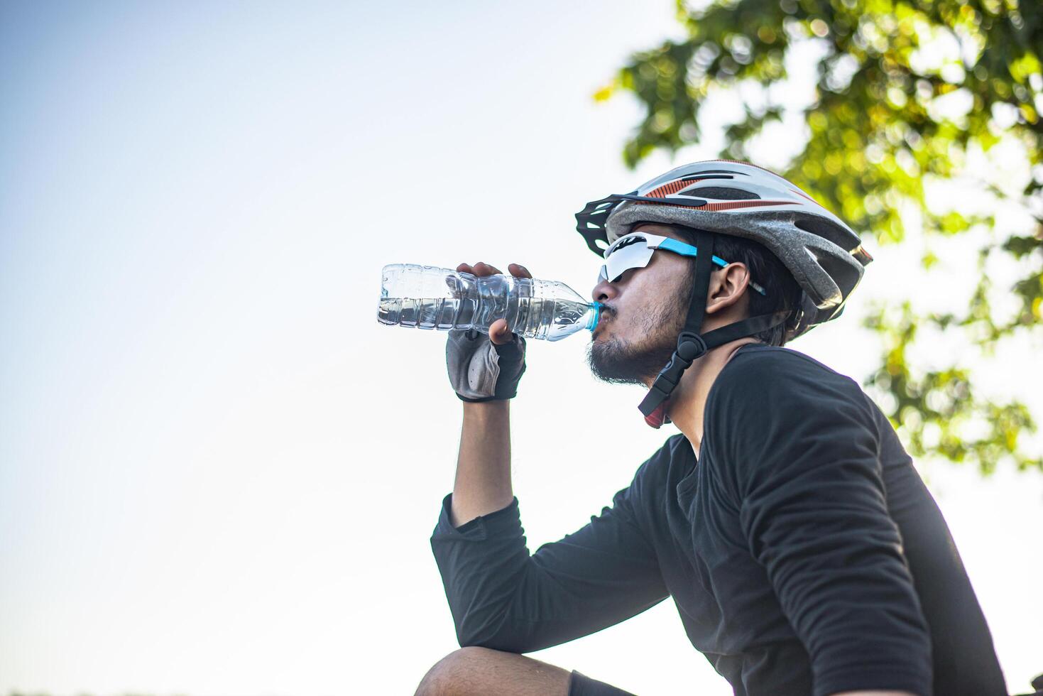 Mountain cyclists stand on the top of the mountain and drink a bottle of water. photo