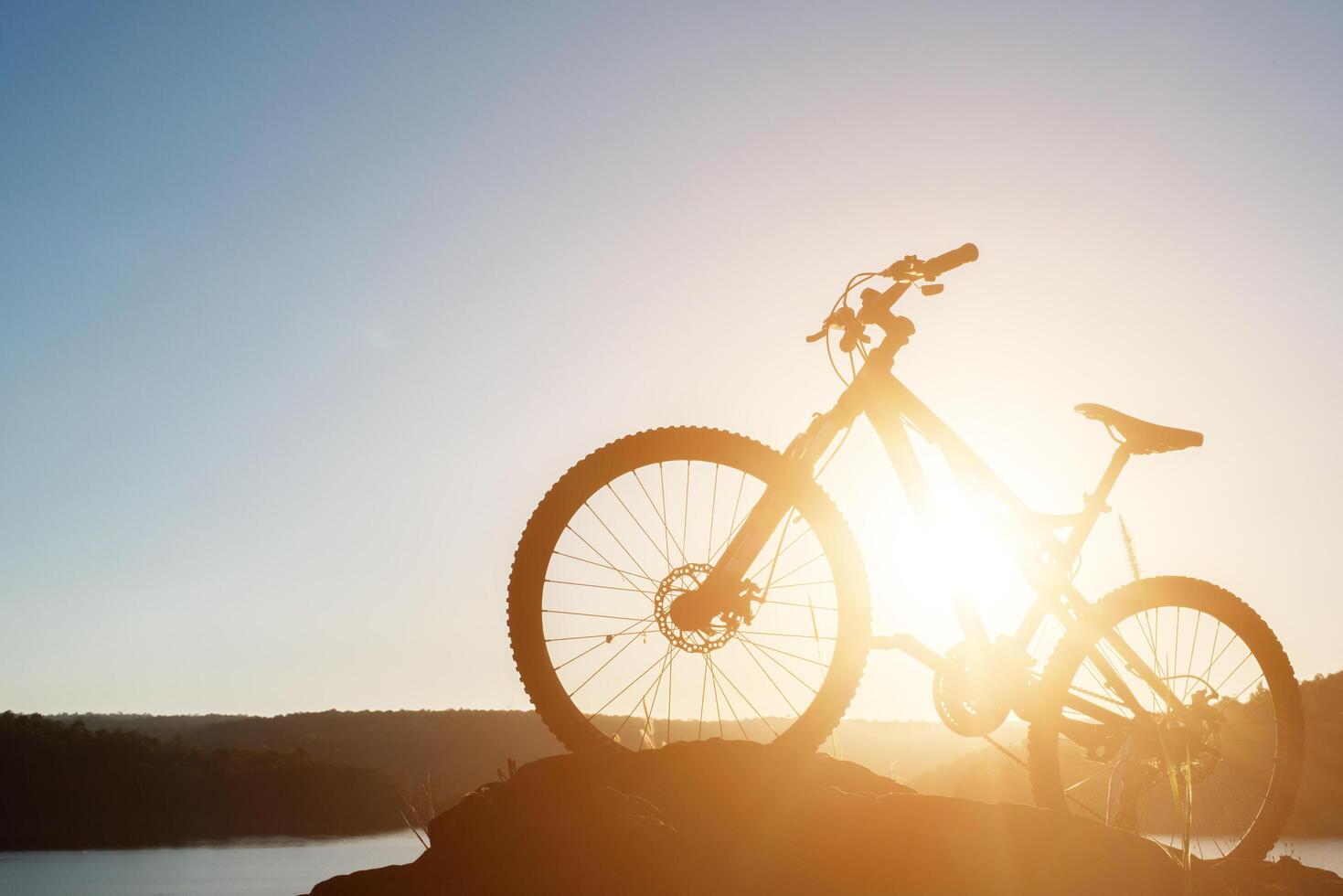 Silhouette Mountain biking on the rock at sky sunset photo