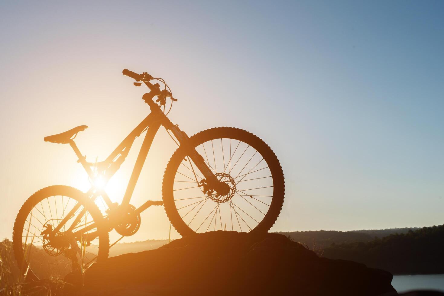 Silhouette Mountain biking on the rock at sky sunset photo