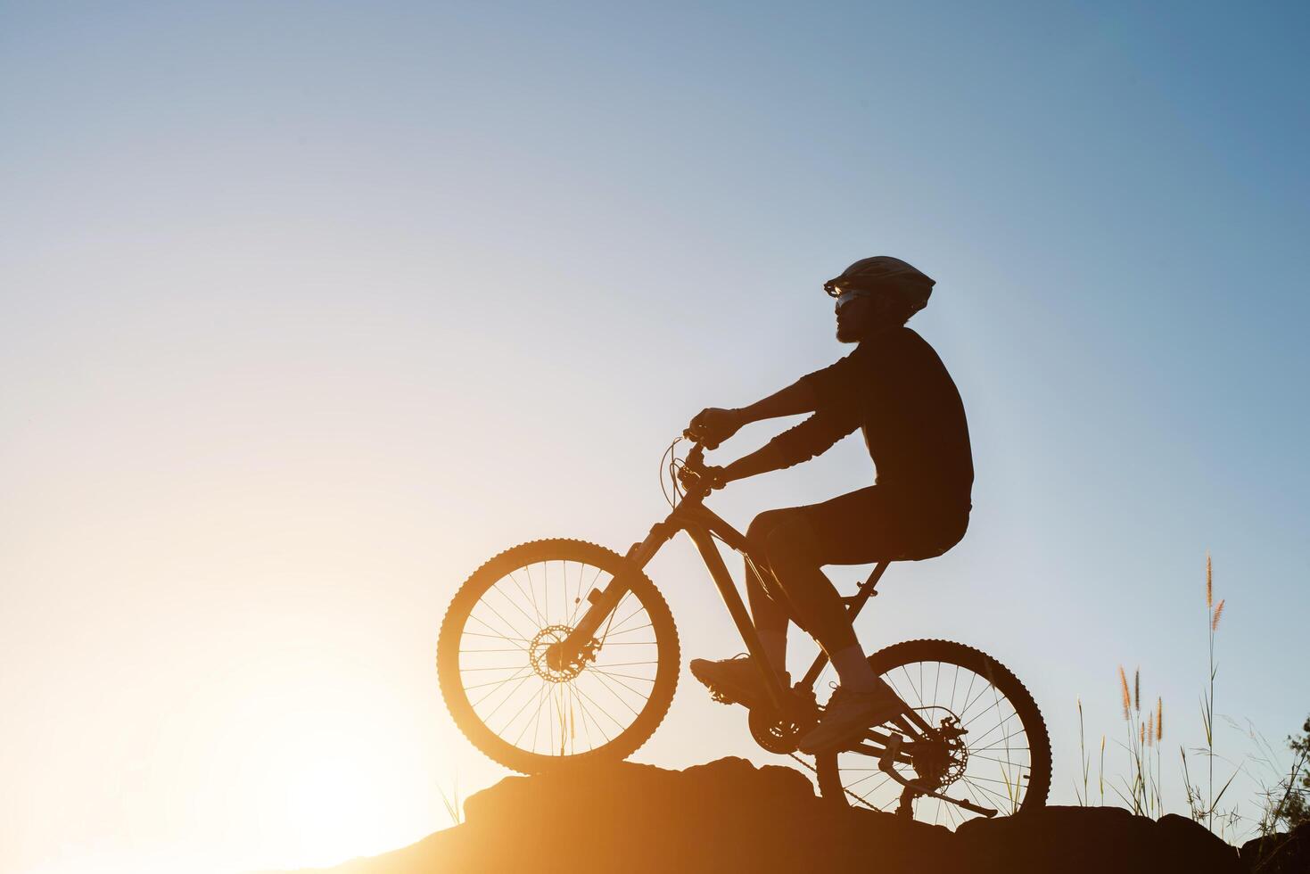 silueta de un hombre en bicicleta de montaña durante la puesta de sol. foto