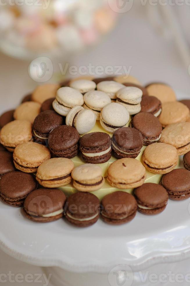 primer plano de la bandeja con mucha diversidad deliciosa pastelería pasteles tartaletas y macarrones en una fila. postres de bayas dulces frescas, multicolores, coloridas, verdes, amarillas, blancas y rosas, bellamente decorados foto