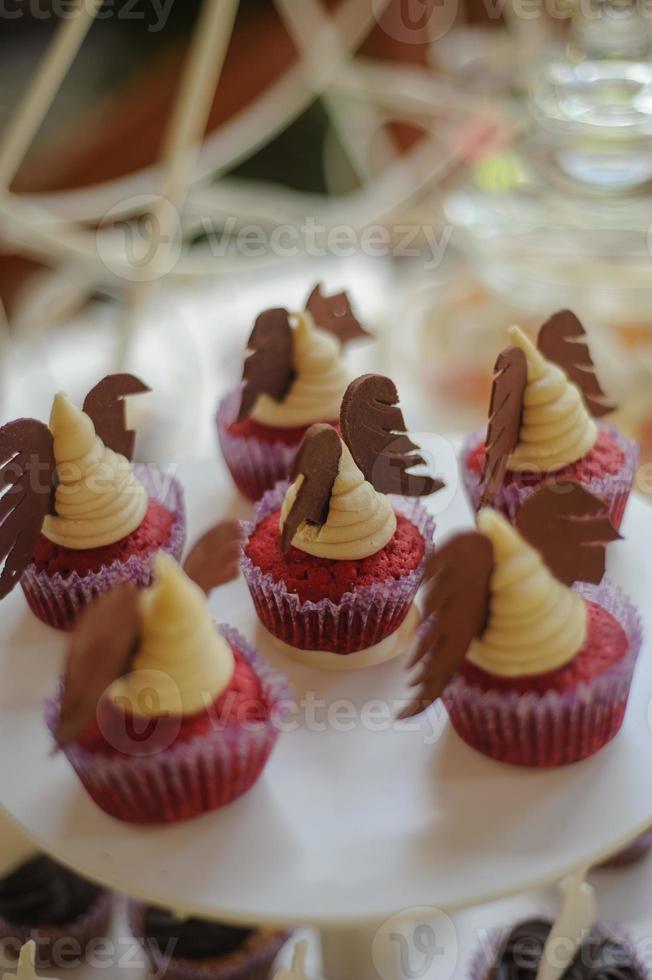 primer plano de la bandeja con mucha diversidad deliciosa pastelería pasteles tartaletas y macarrones en una fila. postres de bayas dulces frescas, multicolores, coloridas, verdes, amarillas, blancas y rosas, bellamente decorados foto