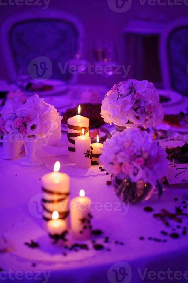 hermosa mesa decorada con adornos florales y velas rojas. noche de navidad o decoración de fiesta de bodas. foto