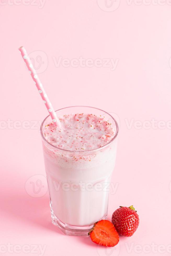 Fresh milkshake with strawberries on pink background. photo