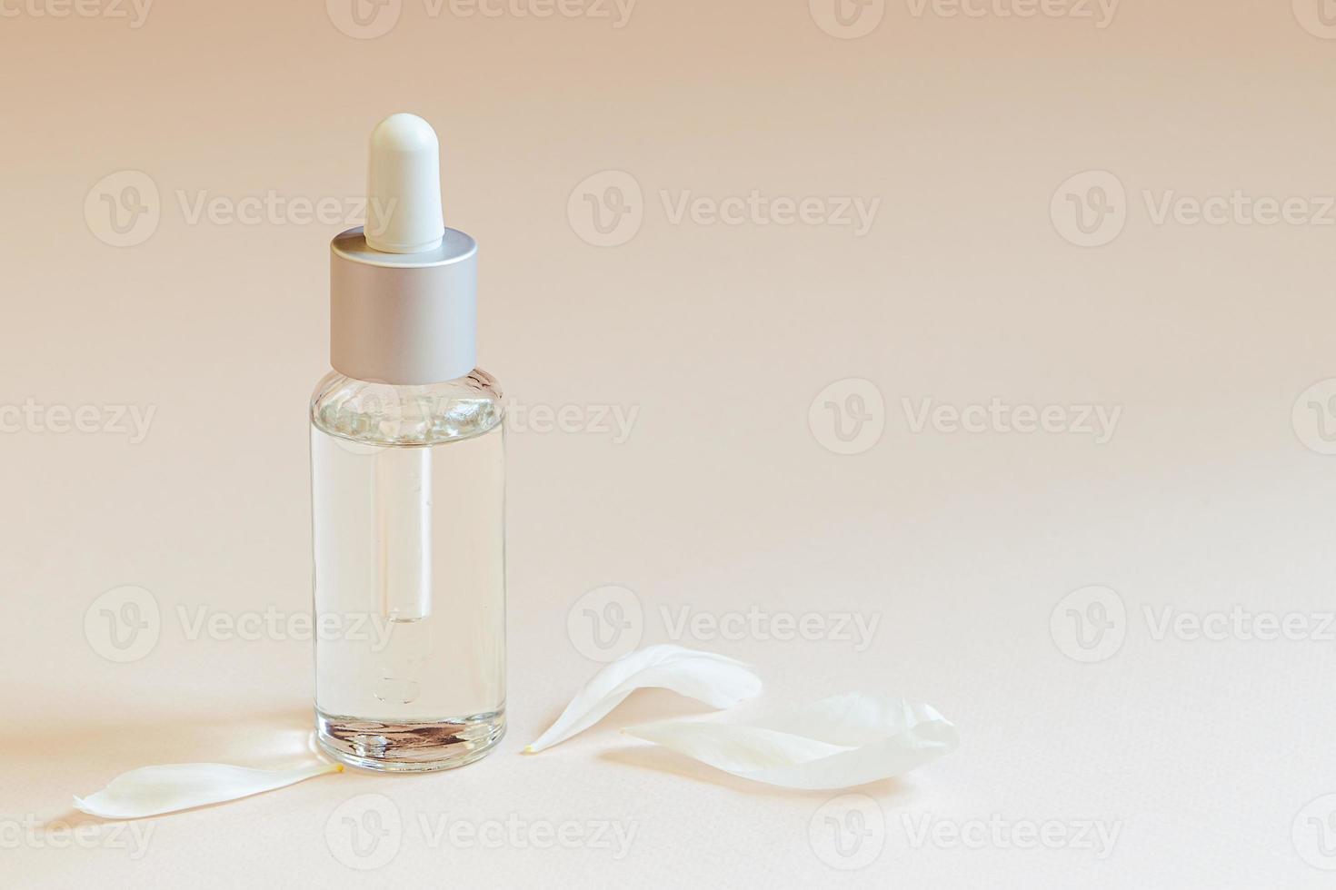 Face serum and white flower petals on trendy pastel beige background. photo