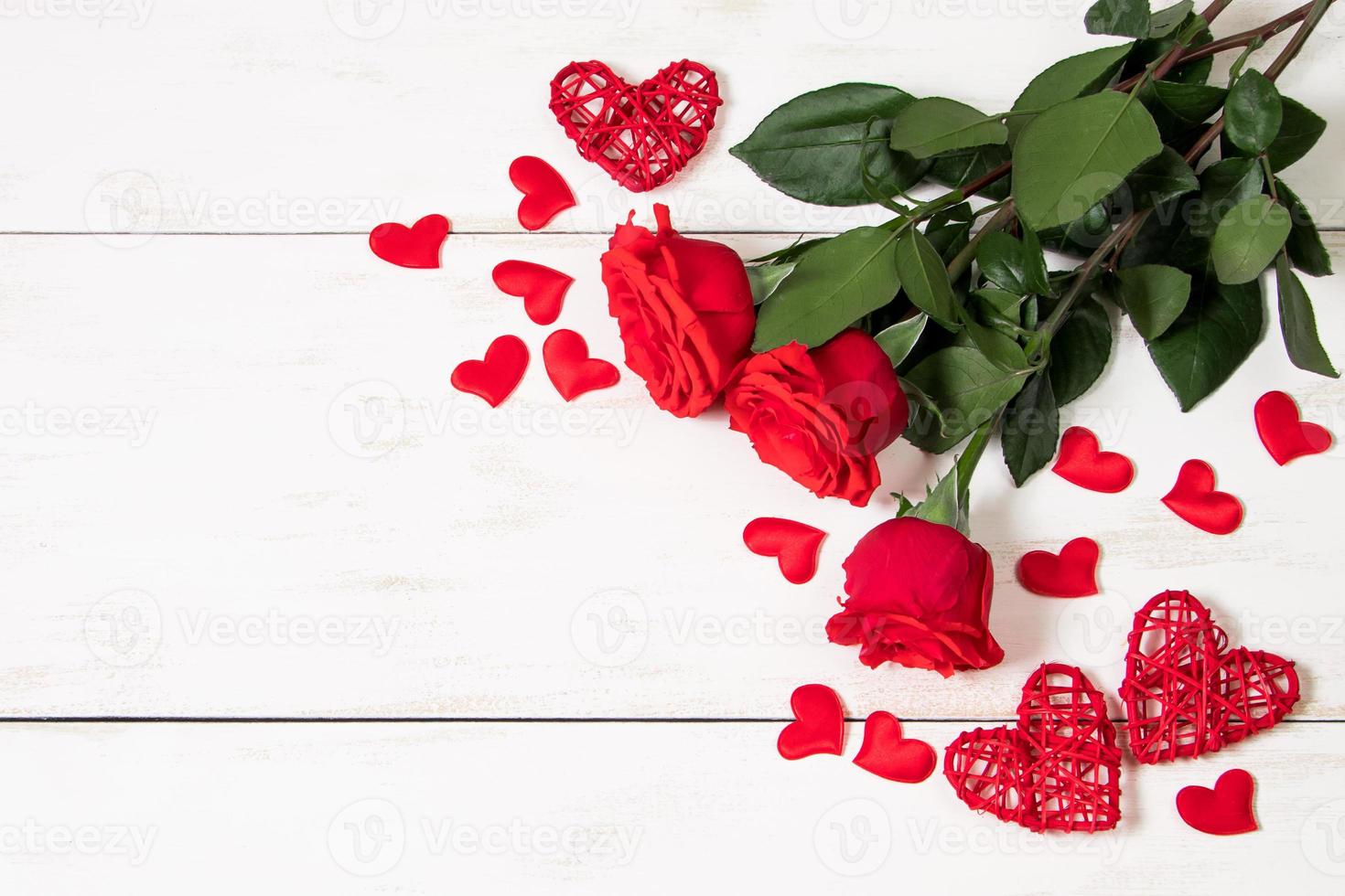 Red roses and hearts on a white wooden background. photo