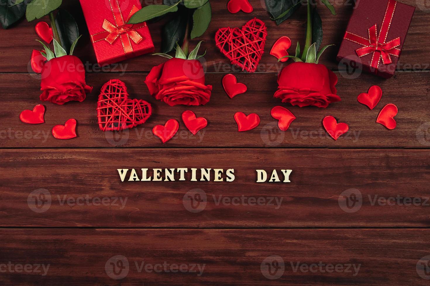 rosas rojas y corazones sobre un fondo de madera oscura. foto