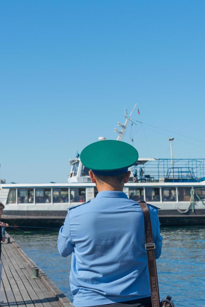 Sevastopol, Crimea-may 31, 2018- The figure of the border guard in a green cap on the background of the pier. photo