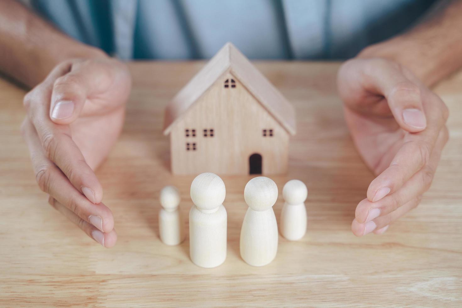 The man Hands protect over wooden peg dolls. planning, saving family,  health care and insurance, family mental health, international day of families photo