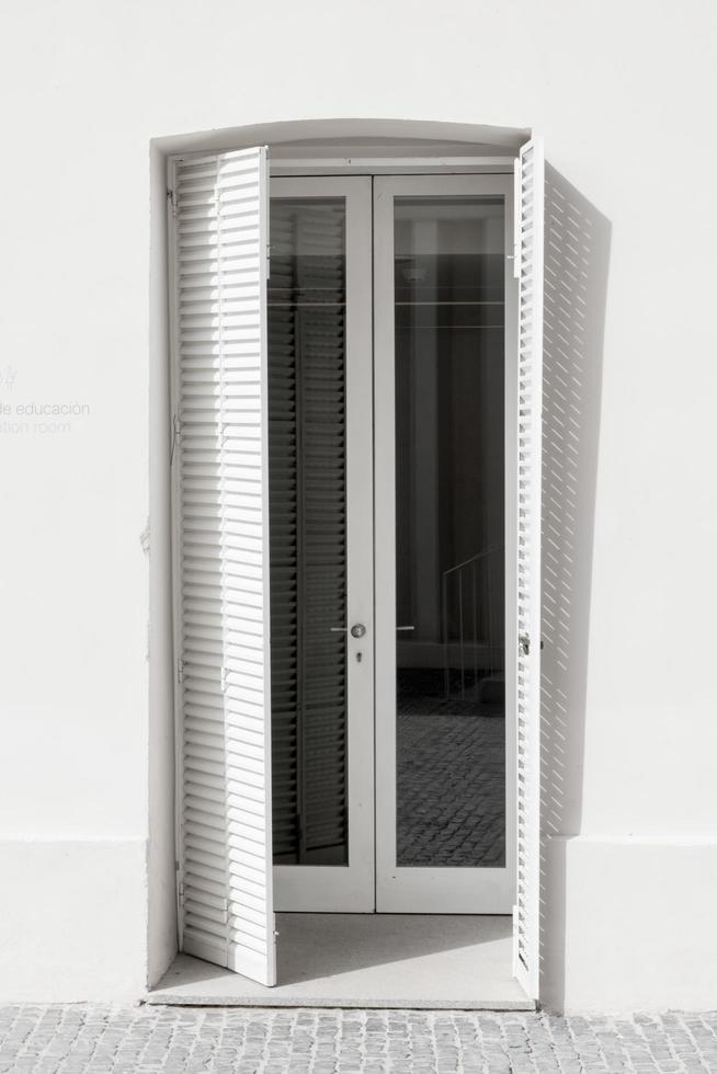White window with open venetian shutters in a white building. No people. Evora, Portugal photo