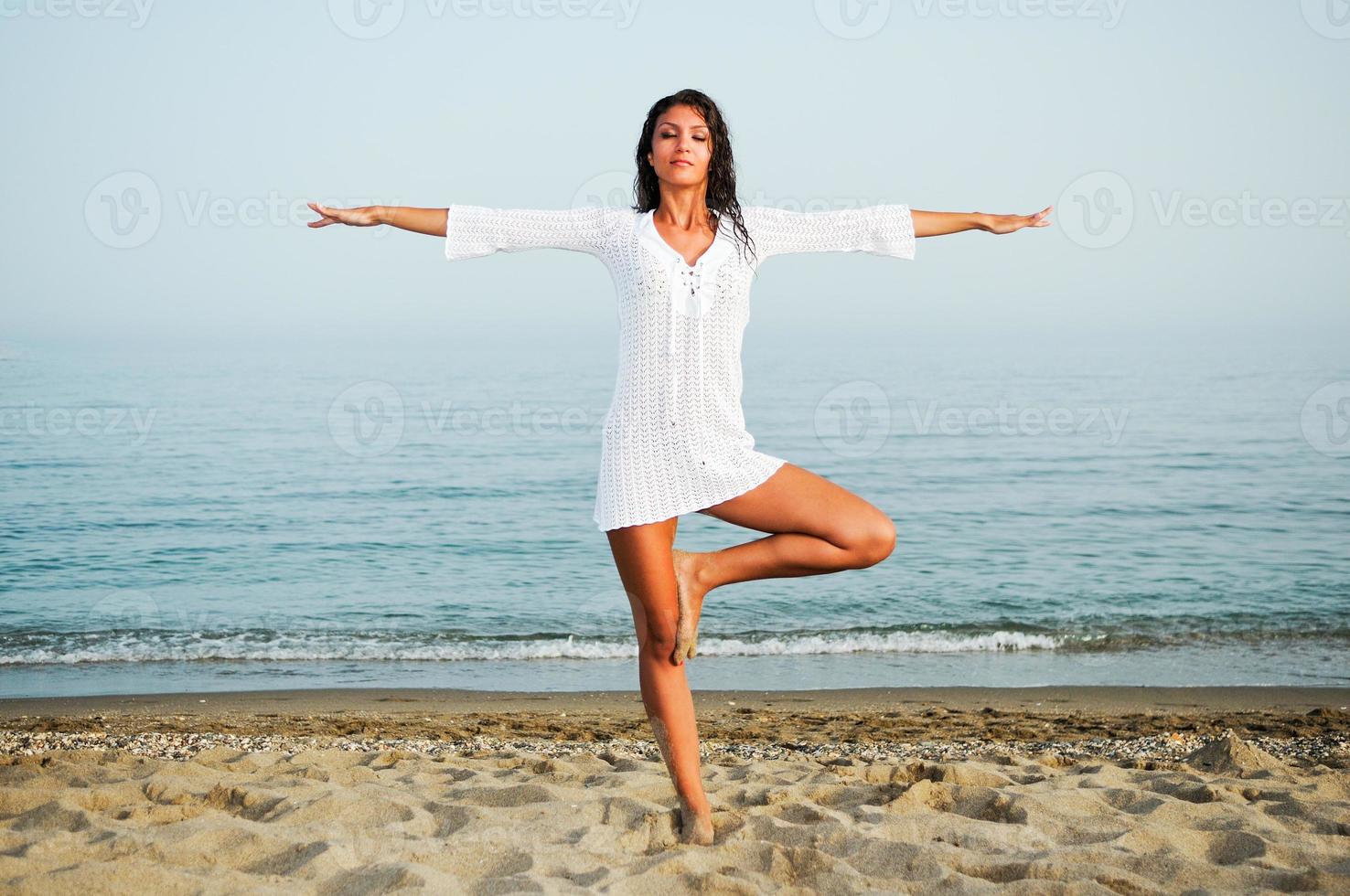 Pretty woman doing yoga on the beach photo