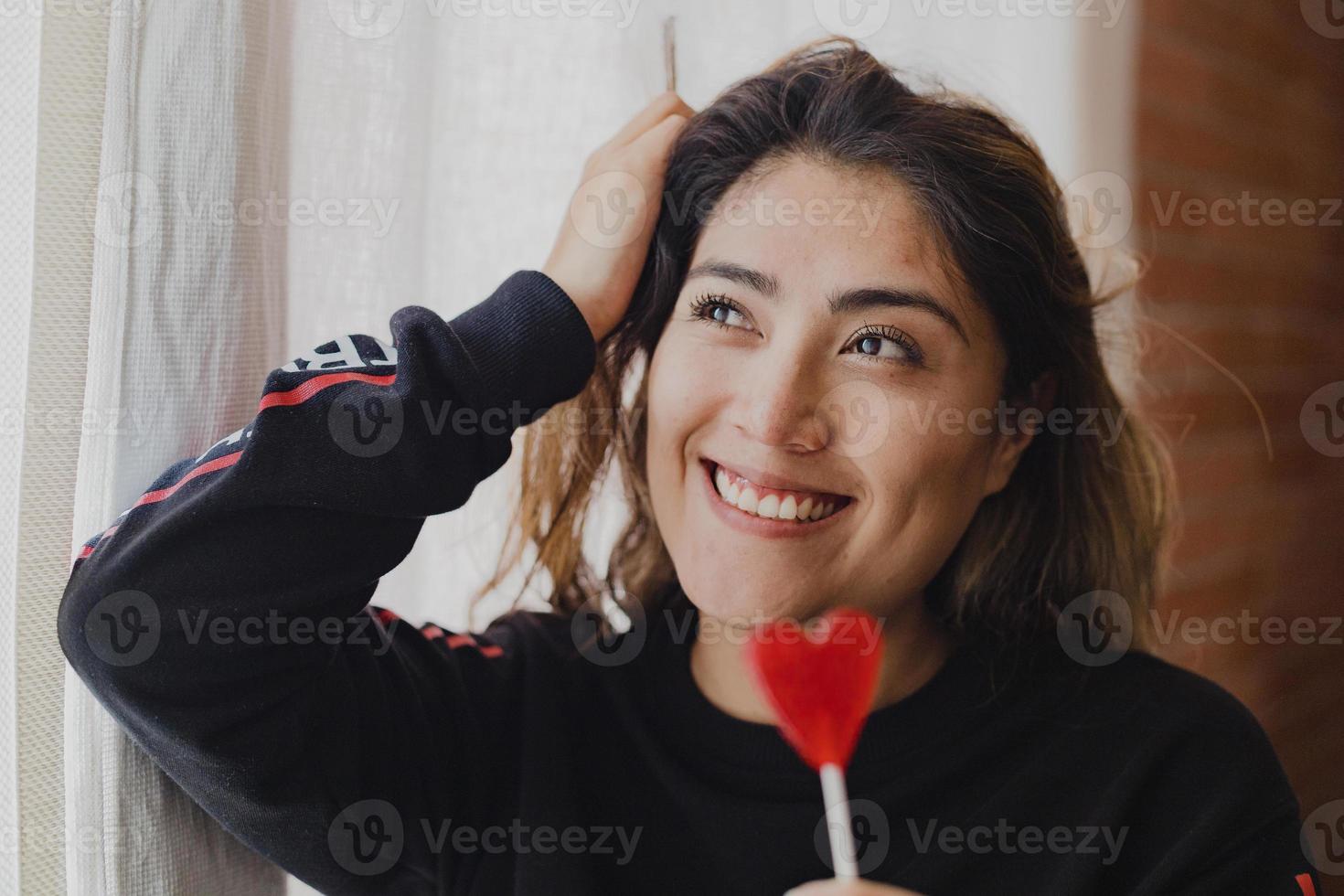 Latin woman in love with a lollipop in her hand in the shape of a heart. Valentine's Day photo