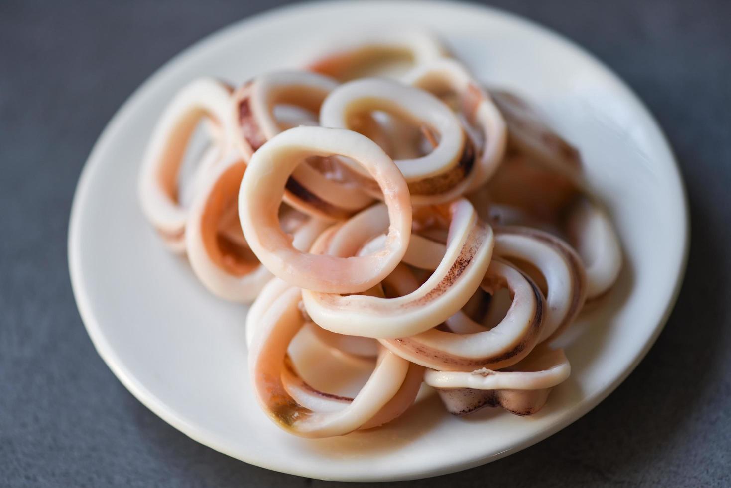 squid rings on white plate, Fresh squid cooked boiled with lettuce vegetable salad on dark background photo