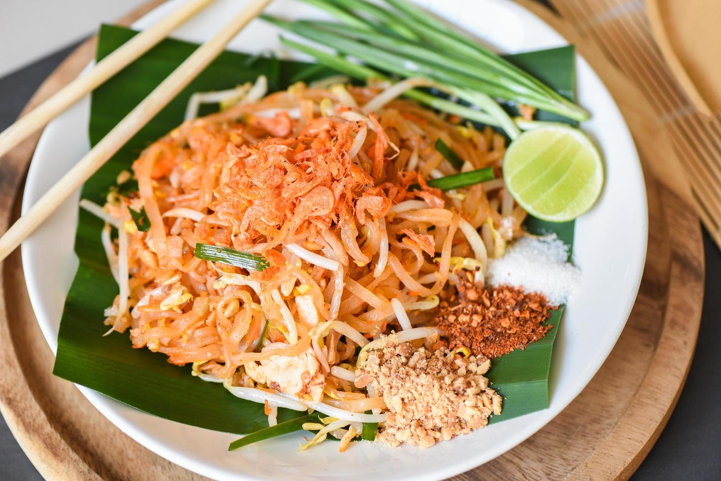 Thai food fried noodle Thai style with prawns bean sprout and garnish peanuts chili powder sugar lemon lime, Stir-fry noodle Pad Thai on plate served on the dining table food - top view photo