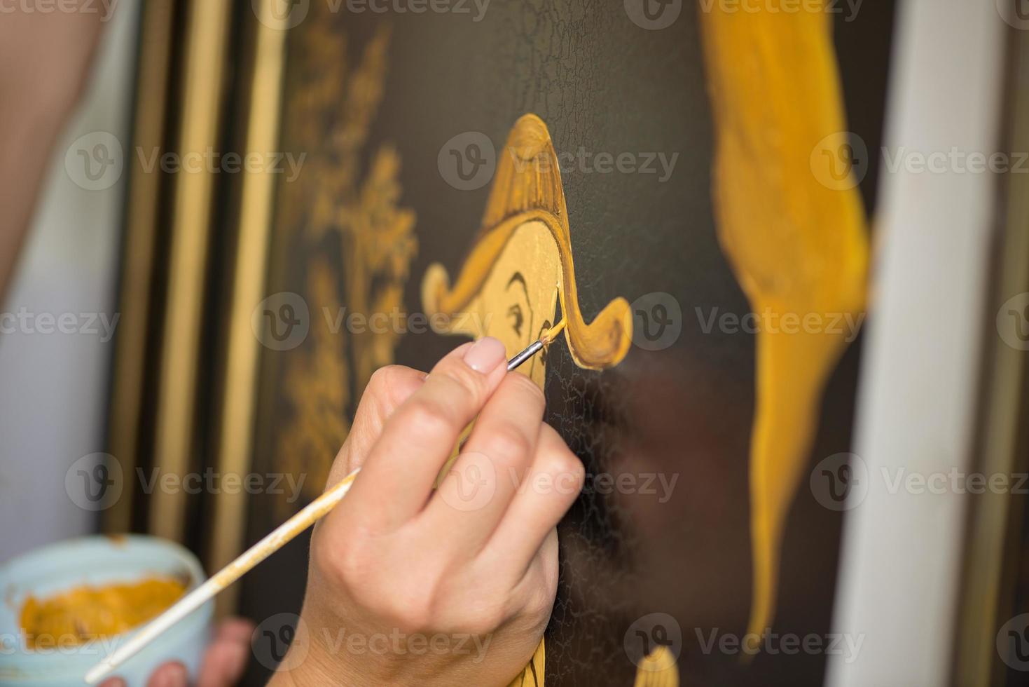 painter decorator draws Chinese pattern of leaves and man, macro shooting photo