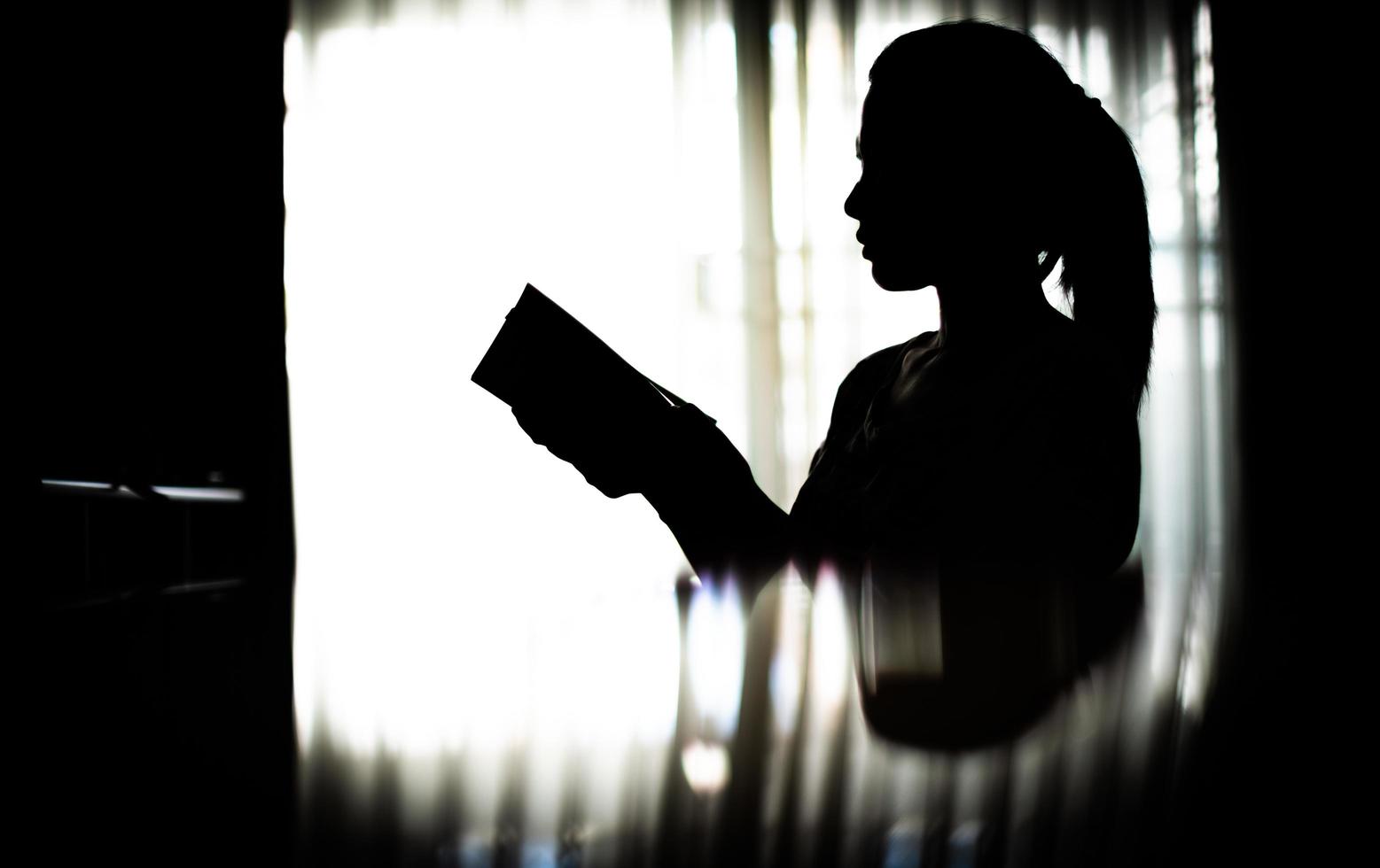 silueta joven leyendo un libro en la sala de estar foto