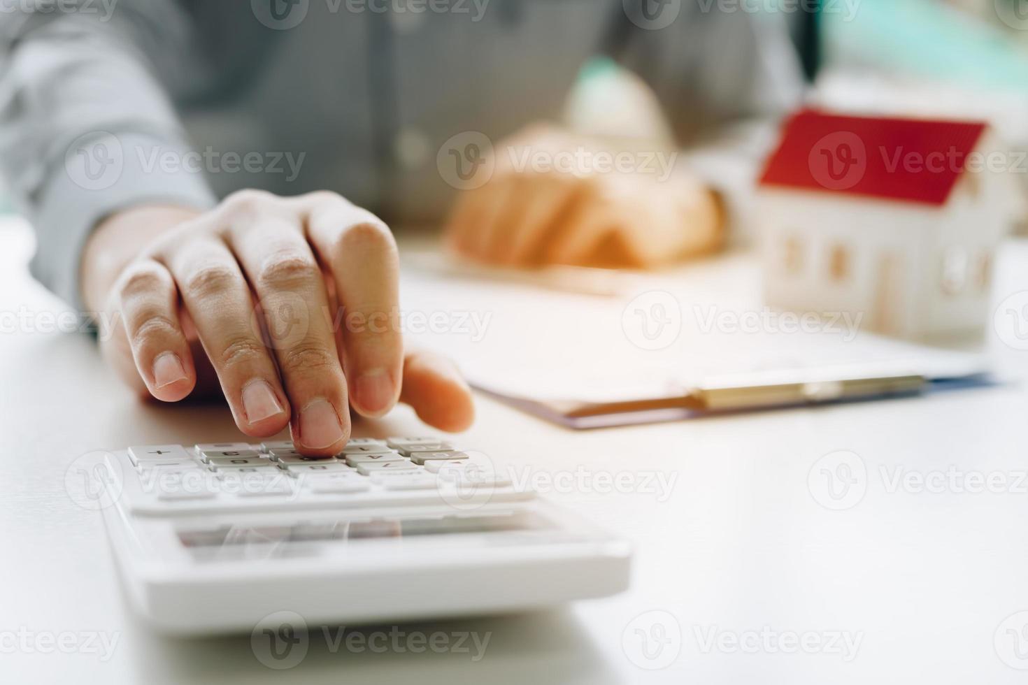 Businessman using calculator calculate budget about house contract mortgage in the office room. photo