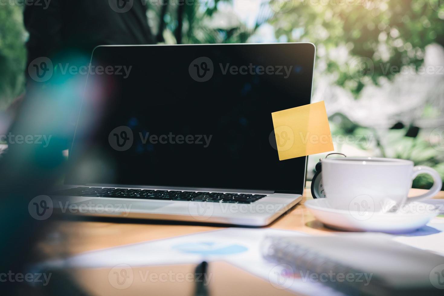 Sticky note pad paste on laptop with coffee cup on wooden desk. photo