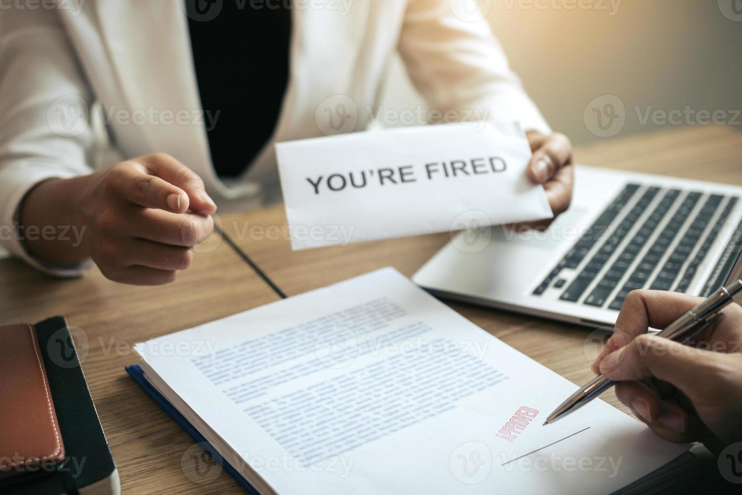 Female manager handed out the dismissal certificate to the male employee while signing the contract to quit from or resign. photo