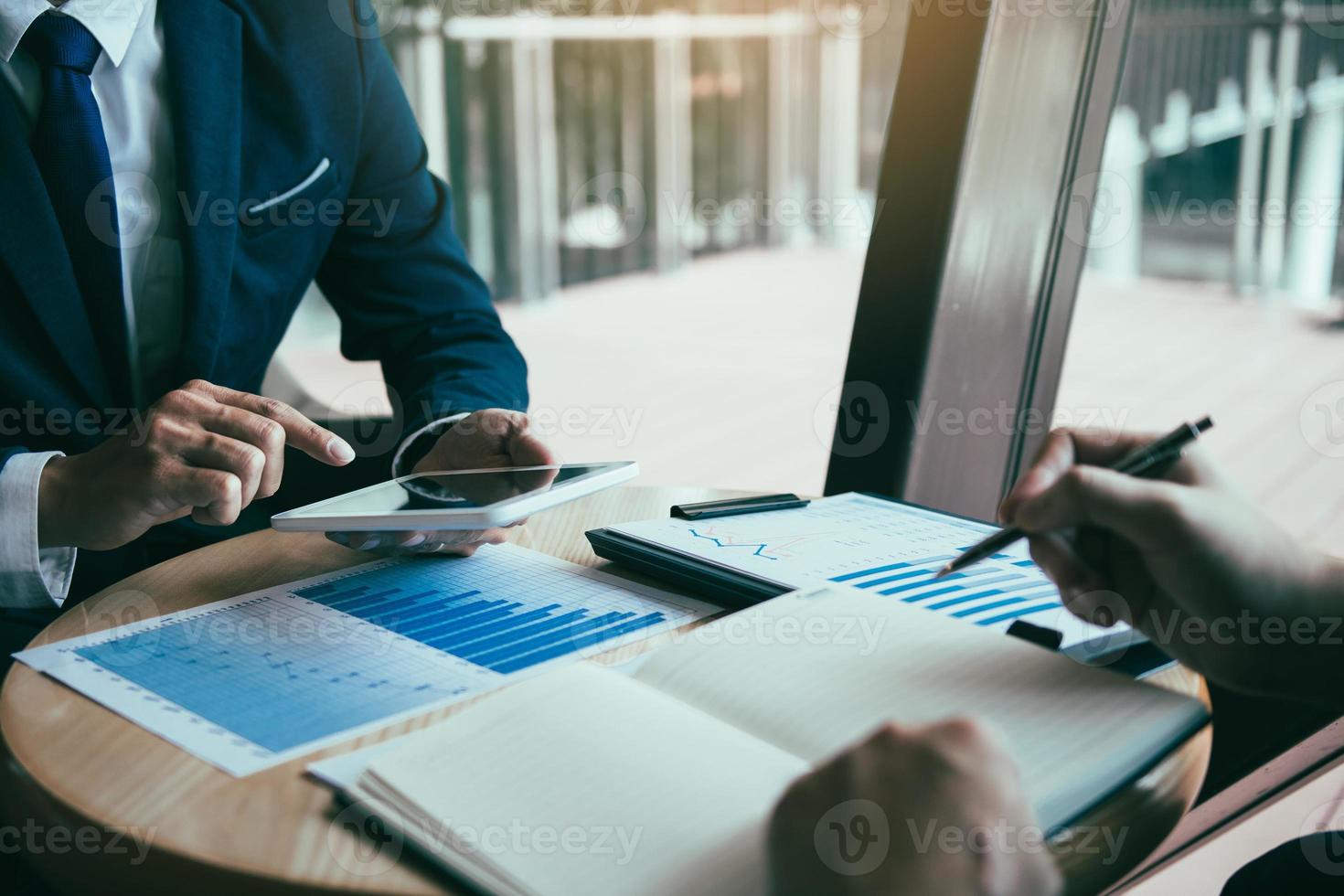Business partnership coworkers using a tablet to chart company financial statements report and profits work progress and planning in office room. photo