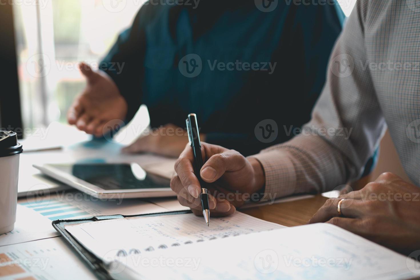 Business partnership coworkers writing cost work progress and using a tablet to analysis graph company financial budget report and planning for future in office room. photo