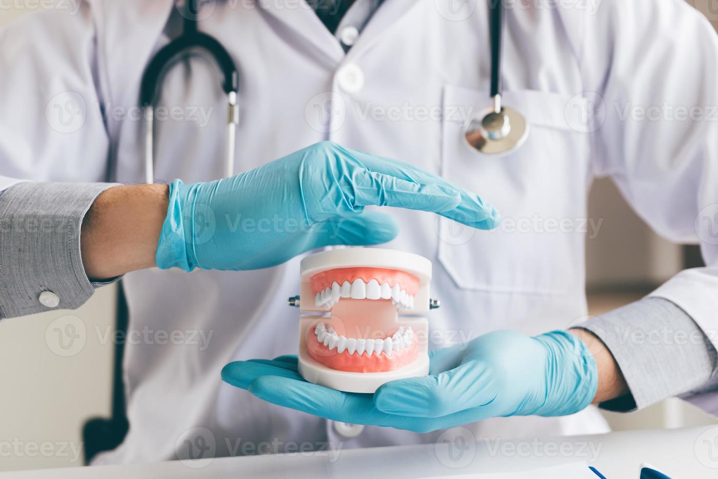 hombre dentista mano asiática protegiendo las dentaduras postizas. foto