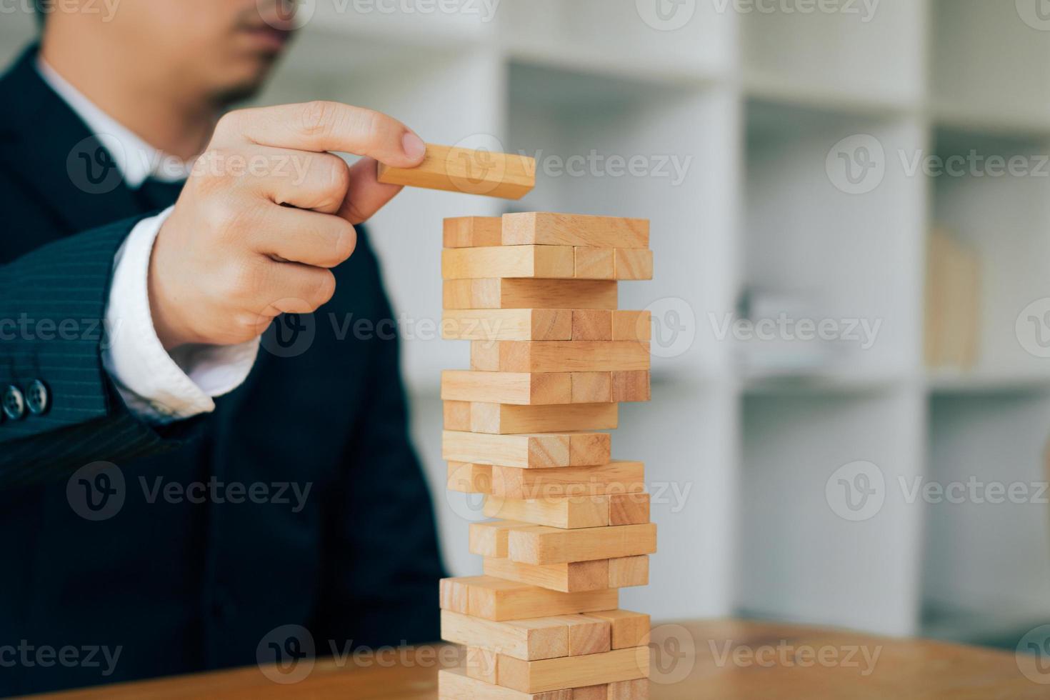 Hand of businessman playing wood blocks stacks game with planning strategy of project management. photo