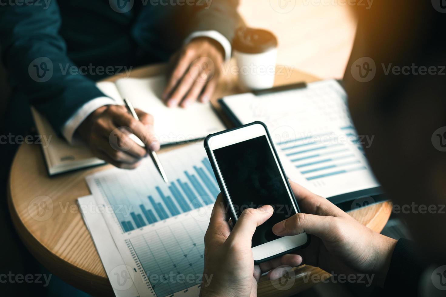 Business partnership coworkers using smartphone to chart company financial statements report and profits work progress and planning in office room. photo