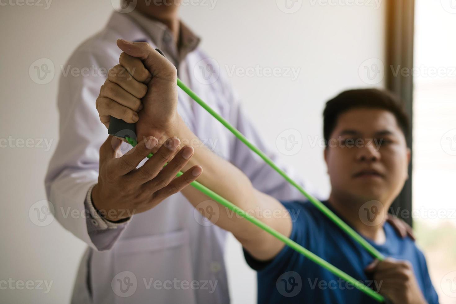 Close up hand patient doing stretching exercise with a flexible exercise band and a physical therapist hand to help in clinic room. photo