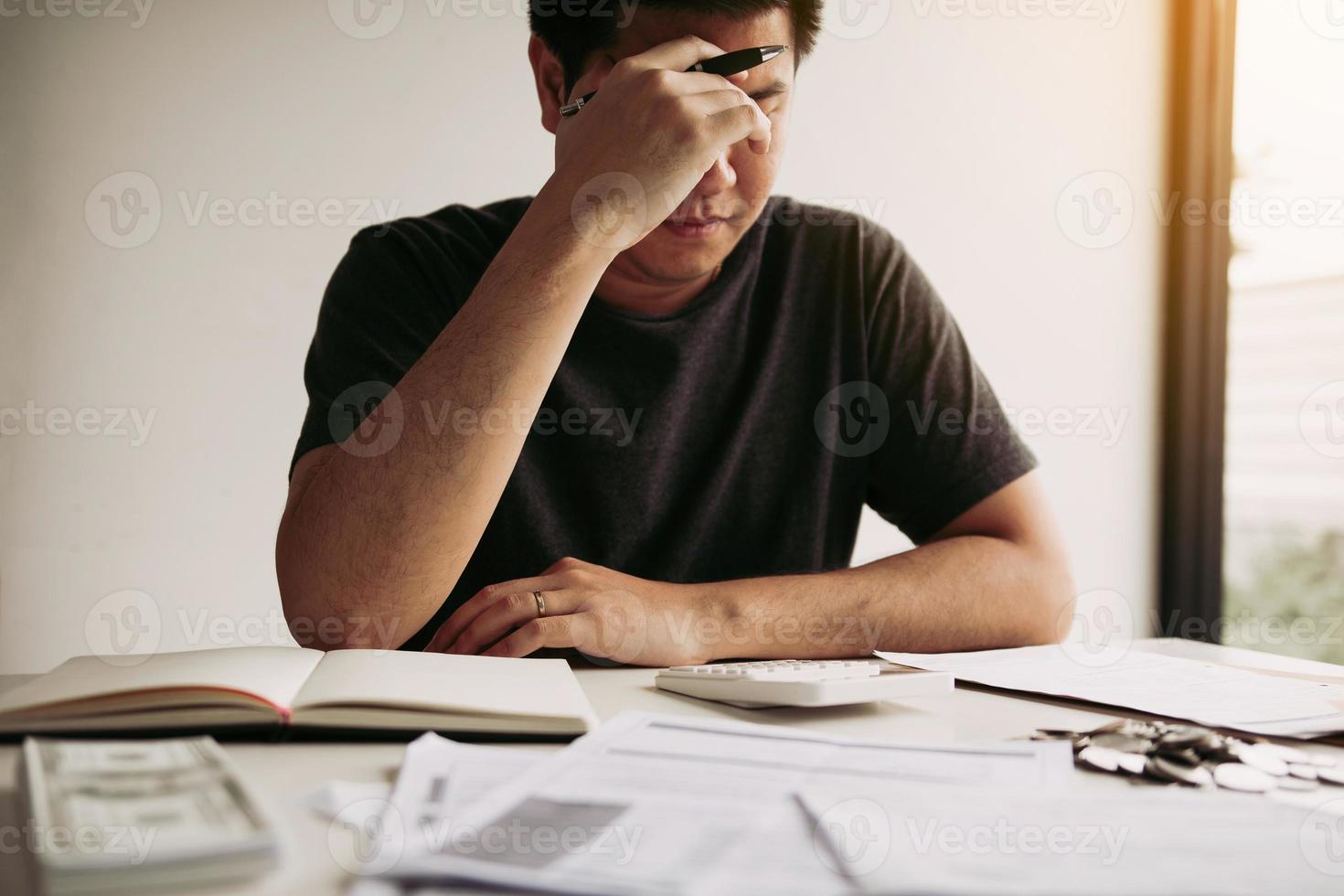 Asian men are stressed about financial problems, with invoices and calculators placed on the table while having stress on problems with home expenses. photo