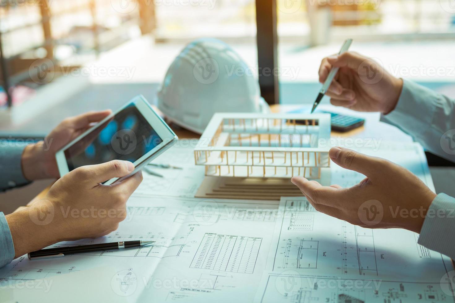 Two engineering working together and using digital tablet looking blueprint and analysis with architectural plan on desk. photo