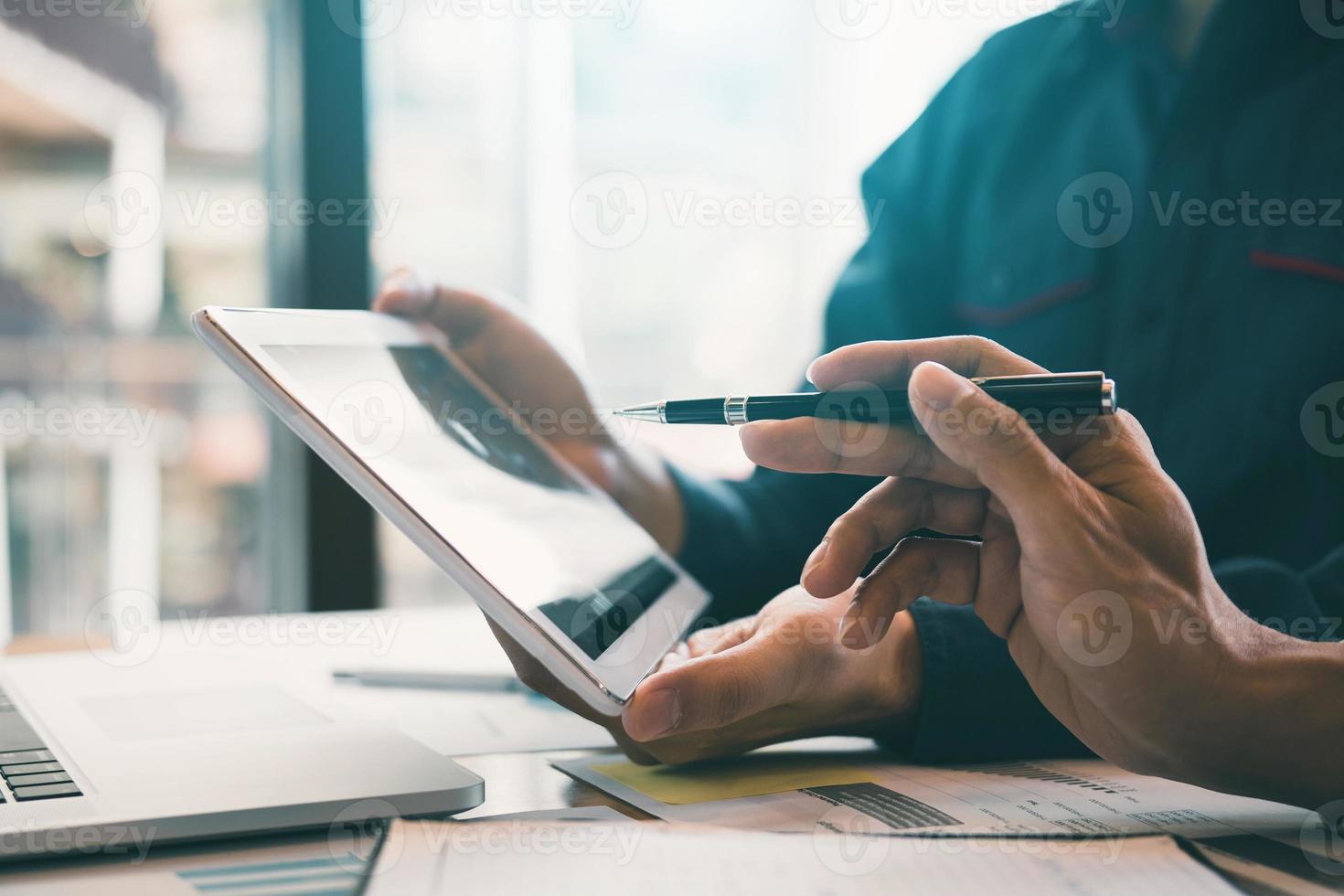 Business partnership coworkers using a tablet to chart company financial statements report and profits work progress and planning in office room. photo